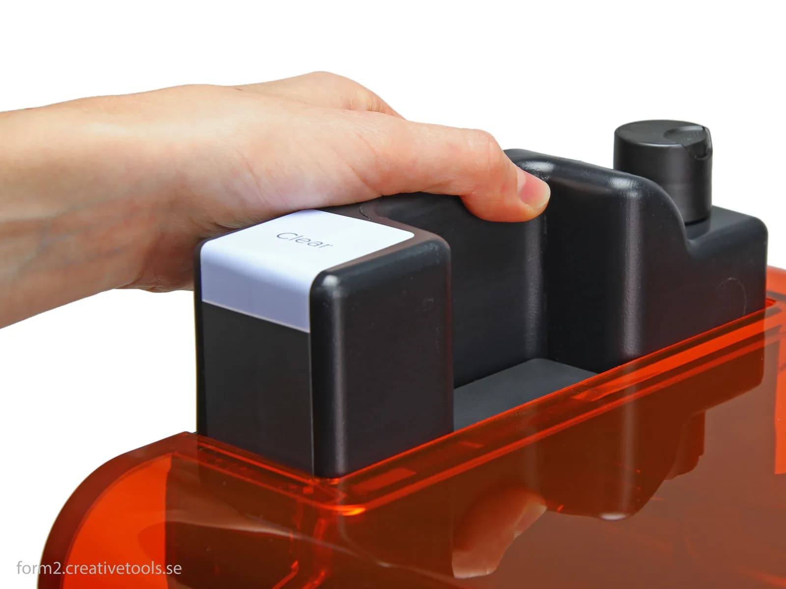 A hand fitting a resin cartridge into a printer with an orange cover